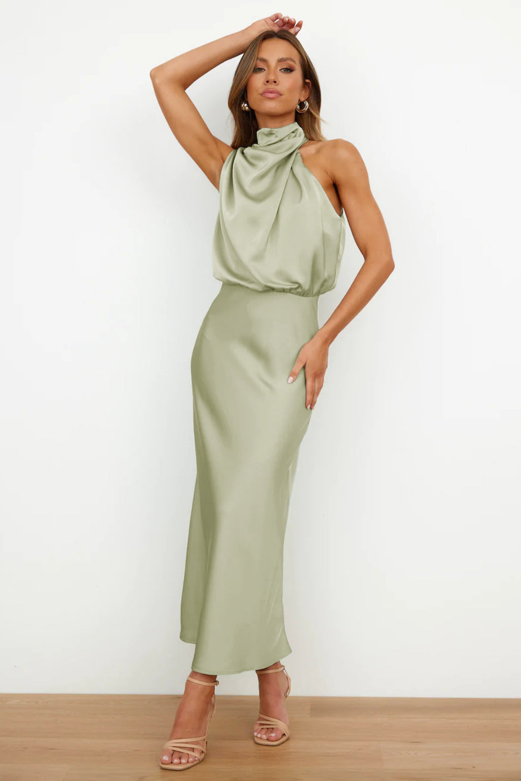 Abito lungo verde salvia in raso con collo alto drappeggiato, senza maniche, indossato da modella. Elegante e moderno, perfetto per eventi formali.