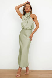 Abito lungo verde salvia in raso con collo alto drappeggiato, senza maniche, indossato da modella. Elegante e moderno, perfetto per eventi formali.