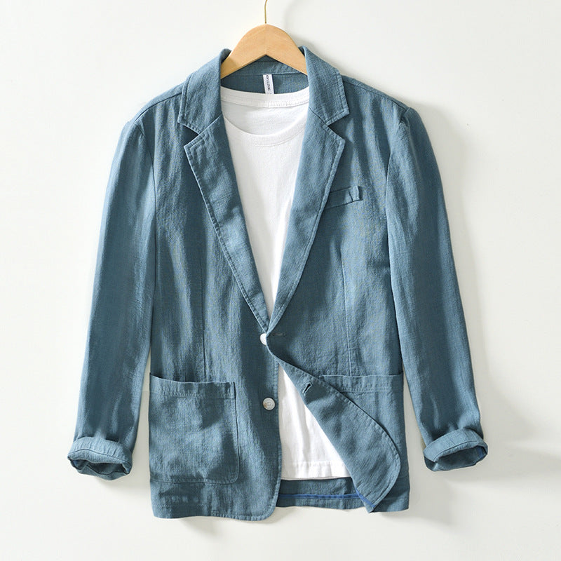 Giacca blazer casual blu in lino, con tasche frontali e maniche arrotolate, appesa su gruccia. Perfetta per look eleganti e informali.