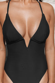 Costume intero nero da donna, scollatura profonda, spalline sottili, moda mare, elegante e moderno, perfetto per l'estate e la spiaggia.