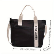 Borsa tote nera in tessuto con manici bianchi, tasca frontale, dimensioni 28x26x11 cm, design moderno, ideale per shopping e uso quotidiano.
