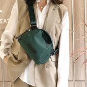 Borsa a tracolla verde scuro su donna con gilet beige e camicia bianca. Accessorio moda elegante, perfetto per look casual e professionali.