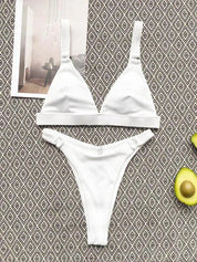 Bikini bianco a triangolo su sfondo geometrico, con avocado e rivista. Costume da bagno estivo, moda mare, stile minimalista.