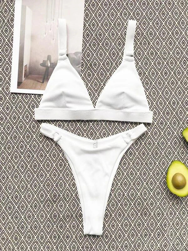 Bikini bianco a triangolo su sfondo geometrico, con avocado e rivista. Costume da bagno estivo, moda mare, stile minimalista.
