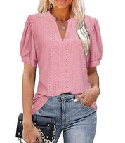 Blusa rosa in pizzo traforato, maniche corte a sbuffo, scollo a V, abbinata a jeans. Moda donna, abbigliamento estivo casual elegante.