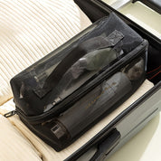 Borsa da viaggio trasparente nera con cerniera, contenente articoli da toeletta, posizionata su una valigia aperta. Accessori viaggio, organizzazione bagagli.