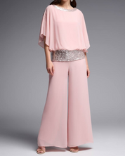 Completo elegante donna rosa con paillettes, maniche ampie e pantaloni larghi. Abbigliamento da cerimonia, moda femminile, stile sofisticato.