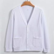 Cardigan bianco in cotone, design classico con scollo a V, bottoni frontali e tasche applicate, appeso su gruccia di legno.