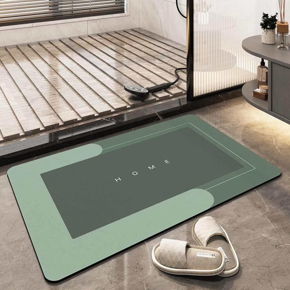 Tappeto da bagno verde con scritta "HOME", design moderno, antiscivolo, posizionato su pavimento in marmo, accanto a pantofole imbottite.