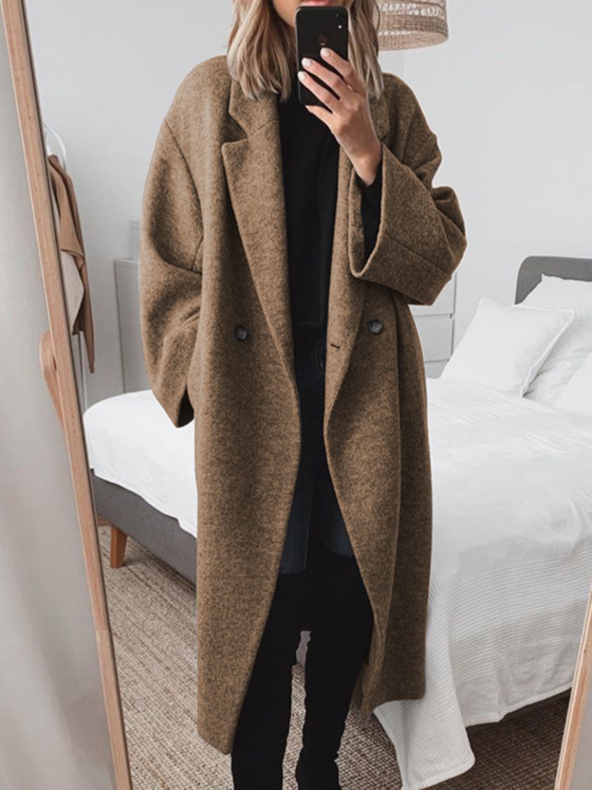 Donna con cappotto oversize marrone, specchio, camera da letto moderna, moda autunnale, abbigliamento casual elegante, selfie allo specchio.