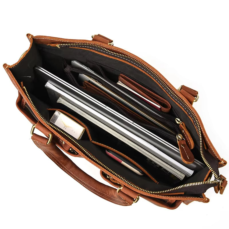 Interno di una borsa in pelle marrone con scomparti organizzati, laptop, tablet e accessori. Elegante e funzionale per lavoro e viaggio.