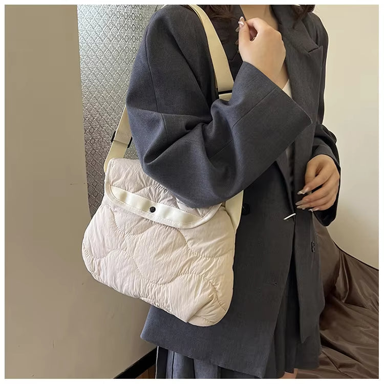 Donna con giacca grigia indossa borsa a tracolla imbottita bianca, moda autunnale, accessorio elegante, stile casual chic, tendenze 2023.