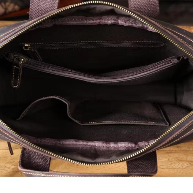 Interno di borsa in pelle marrone con cerniera, tasche multiple e scomparti organizzativi. Design elegante e funzionale per uso quotidiano.