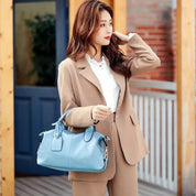 Donna elegante con borsa a mano blu, indossa un completo beige. Moda femminile, accessori di tendenza, stile autunnale.