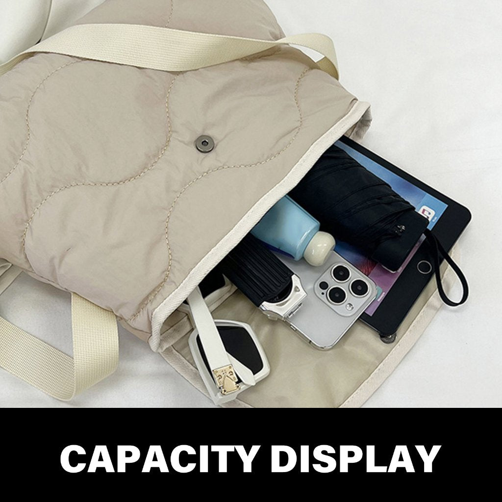 Borsa beige trapuntata aperta con smartphone, tablet, ombrello, crema e occhiali all'interno. Mostra capacità e versatilità.