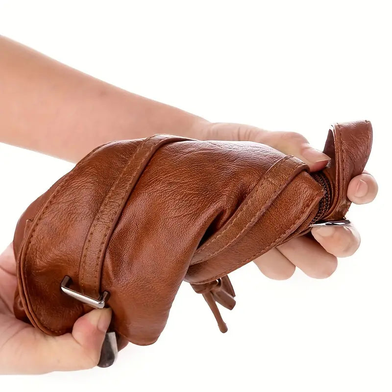 Mani che tengono una borsa a tracolla in pelle marrone, morbida e pieghevole, con cerniera e fibbie in metallo. Accessorio moda elegante e versatile.