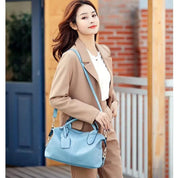 Donna con borsa a tracolla in pelle blu, indossa un elegante cappotto beige. Moda autunnale, accessori di tendenza, look casual chic.