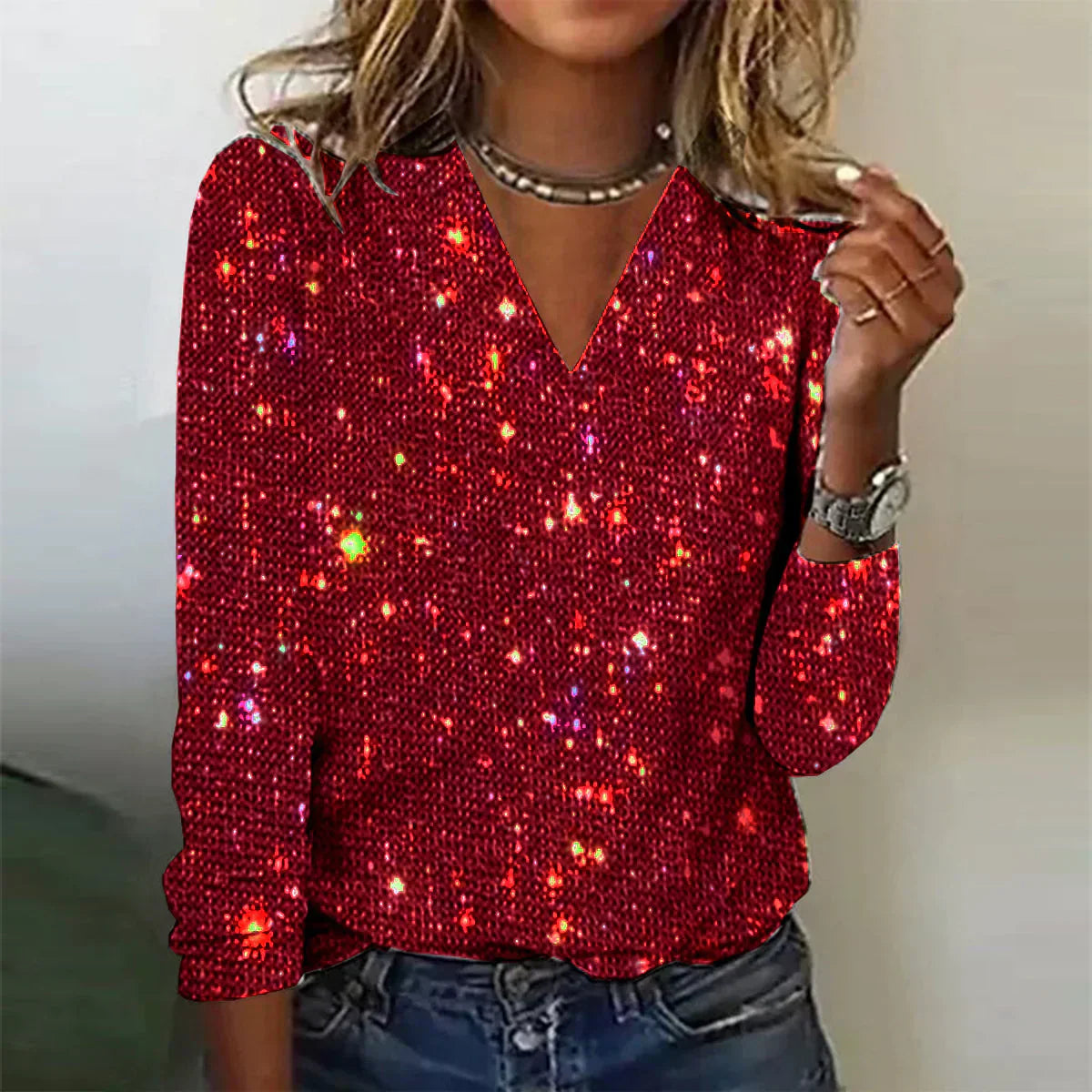 Maglia rossa con paillettes scintillanti, maniche lunghe, scollo a V, indossata da donna. Perfetta per feste e occasioni speciali.