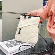 Borsa a tracolla bianca in nylon con zip, design moderno, indossata da una persona in felpa rosa. Accessorio moda casual, ideale per shopping.