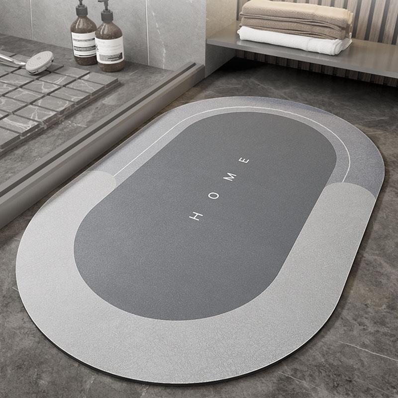 Tappeto da bagno ovale grigio con scritta "HOME", design moderno, antiscivolo, ideale per bagno elegante, pavimento in piastrelle.