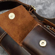 Borsa in pelle marrone con chiusura a bottone in ottone, dettagli cuciti a mano, tasca interna in pelle scamosciata. Accessorio moda elegante e resistente.