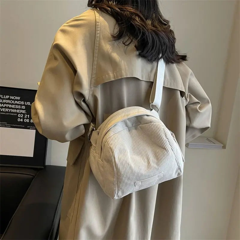 Cappotto beige donna con borsa a tracolla bianca in tessuto a coste, moda autunno, stile casual, accessori femminili eleganti.