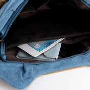 Borsa in tessuto blu con tasca interna contenente un tablet bianco e un portafoglio azzurro. Accessori moda, tecnologia portatile, organizzazione.
