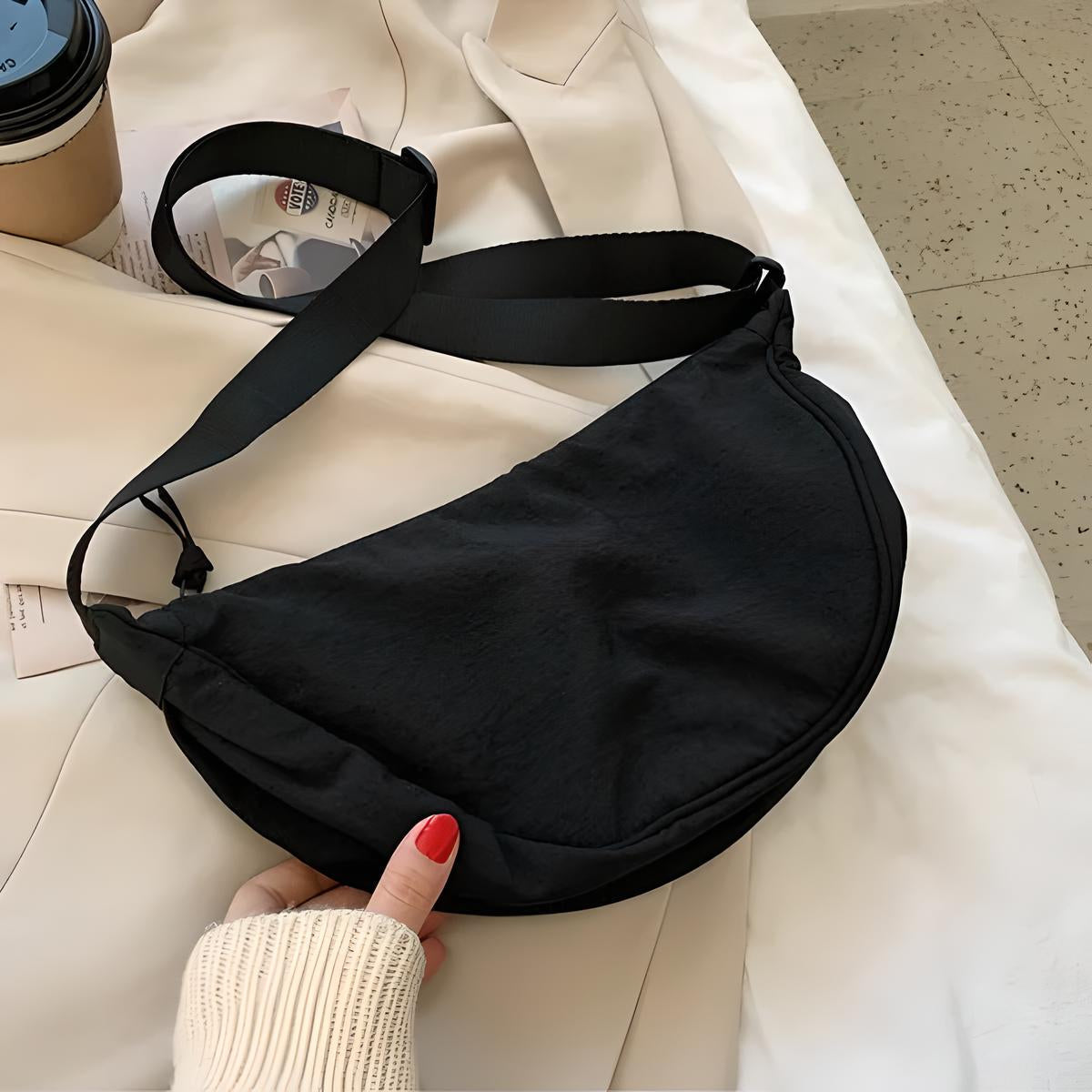 Borsa a tracolla nera su giacca beige, mano con smalto rosso. Accessorio moda donna, stile casual, perfetto per shopping e viaggi.