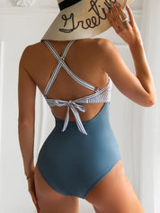 Donna in costume intero blu con dettagli a righe, cappello di paglia con scritta. Moda mare estiva, abbigliamento da spiaggia elegante.