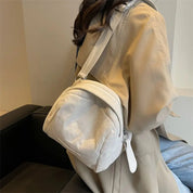 Zaino in velluto a coste bianco su donna con cappotto beige, moda autunno, accessorio casual elegante, ideale per shopping e viaggi urbani.