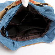 Zaino in tela blu e marrone aperto, con ampio scomparto interno e tasche multiple. Ideale per viaggi, scuola e uso quotidiano.