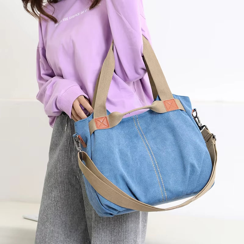 Borsa a tracolla in denim blu con manici beige, indossata da una persona con maglia viola. Design casual, ideale per moda quotidiana.