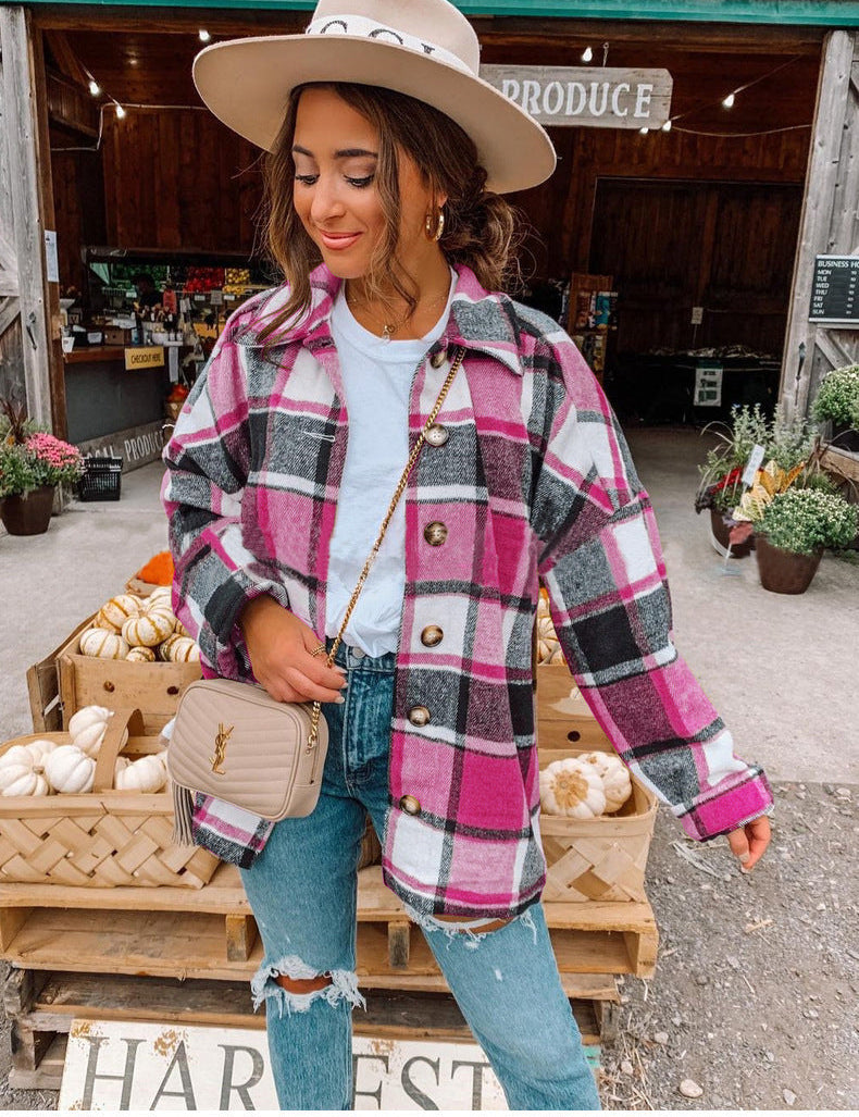 Donna con cappotto a quadri rosa e bianco, jeans strappati, borsa beige, cappello beige, davanti a negozio di prodotti agricoli. Moda autunnale casual.