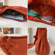 Borsa a tracolla arancione con cerniera, tasche interne, contenente fotocamera, libro e caramelle. Design moderno, ideale per viaggi e uso quotidiano.