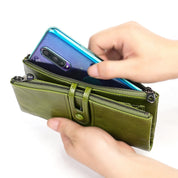 Mani inseriscono uno smartphone in un portafoglio verde in pelle con cerniera. Accessorio moda, portafoglio donna, custodia telefono.