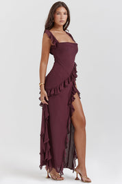 Abito lungo elegante bordeaux con volant, spacco laterale e spalline sottili. Perfetto per eventi serali e cerimonie. Moda donna sofisticata.