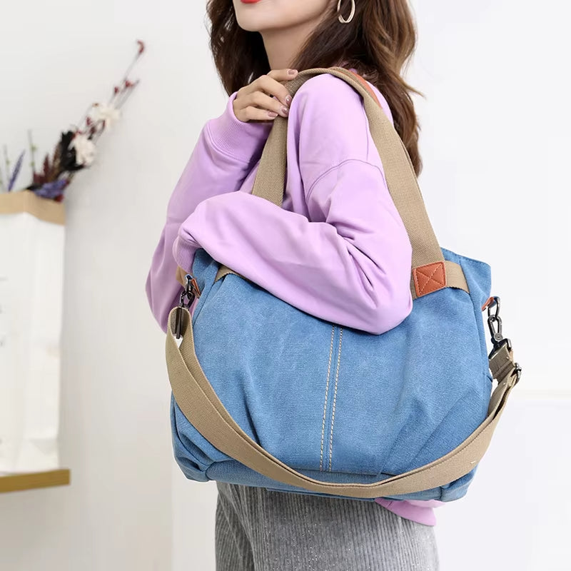 Donna con borsa a tracolla in tela blu, manici beige, indossa felpa viola. Accessorio moda casual, ideale per shopping e uso quotidiano.