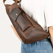 Zaino a tracolla in pelle marrone, design elegante e pratico, indossato su spalla, ideale per viaggi e uso quotidiano. Accessorio moda uomo.