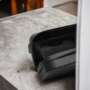 Borsa da toilette nera su tavolo in cemento, design moderno e minimalista, ideale per viaggi, accessori da bagno, organizer compatto ed elegante.