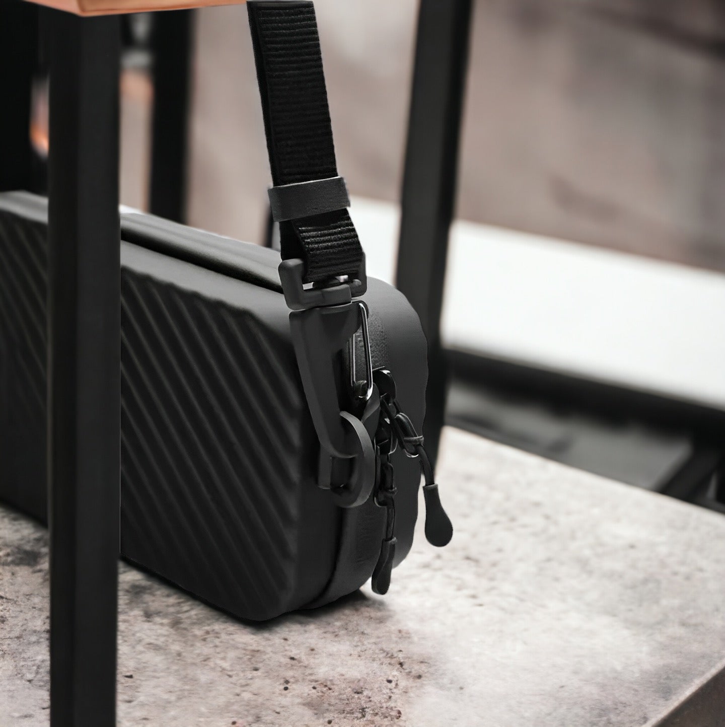 Borsa a tracolla nera su sedia, design moderno con cerniere e ganci robusti. Accessorio moda unisex, ideale per viaggi e uso quotidiano.