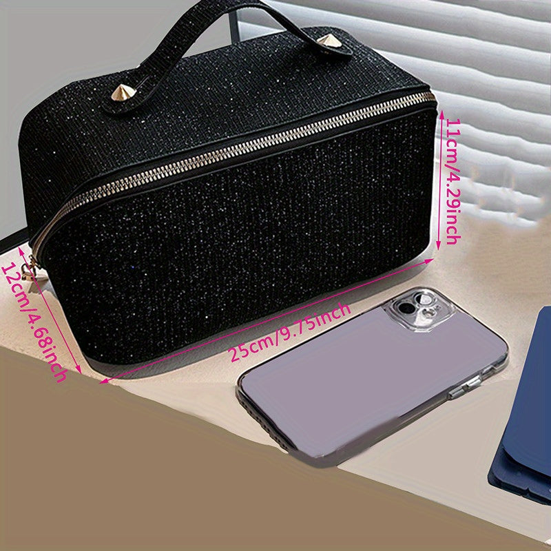 Borsa cosmetica nera glitterata con cerniera, dimensioni 25x12x11 cm, accanto a smartphone con cover trasparente. Accessori moda eleganti.