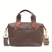 Borsa a mano in tessuto marrone con manici e tracolla regolabile, dettagli in pelle marrone chiaro, accessori in metallo dorato. Elegante e versatile.