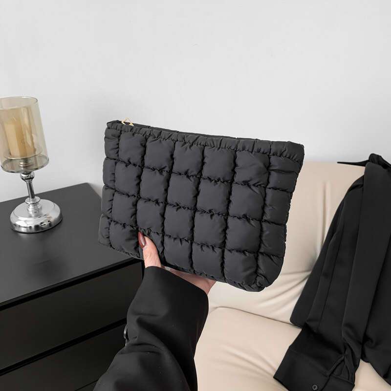 Borsa a mano trapuntata nera, elegante e moderna, su sfondo minimalista. Accessorio moda donna, perfetto per look casual e chic.