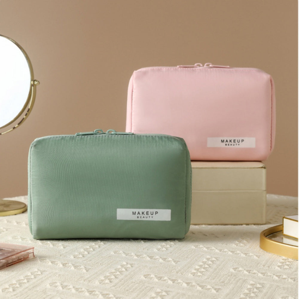 Due astucci per trucco in tessuto, uno verde e uno rosa, su scatole beige. Specchio rotondo sullo sfondo. Accessori cosmetici eleganti e pratici.