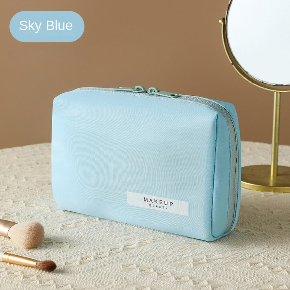 Astuccio trucco azzurro su tavolo con specchio e pennelli. Borsa cosmetica elegante, ideale per organizzare prodotti di bellezza.