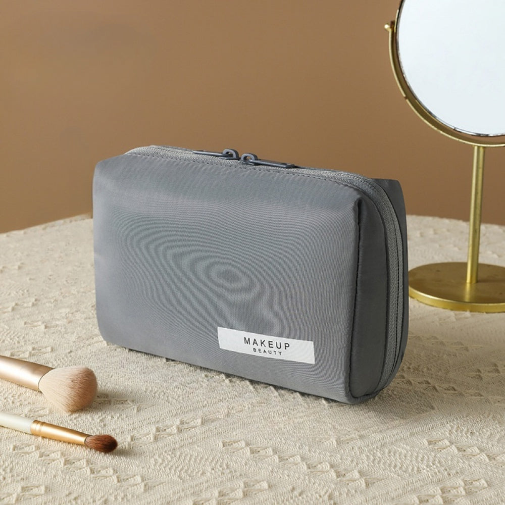 Astuccio trucco grigio su tavolo con specchio e pennelli, design elegante, ideale per organizzare cosmetici. Accessorio beauty essenziale.