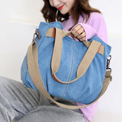 Donna con borsa a tracolla in tela blu, dettagli in pelle marrone e manici beige. Moda casual, accessorio femminile trendy.