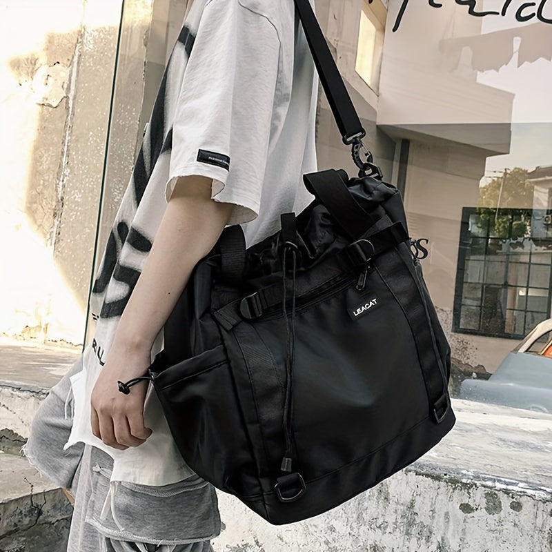 Borsa a tracolla nera unisex, stile casual, in tessuto resistente, con tasche multiple e chiusura a coulisse, indossata da una persona.
