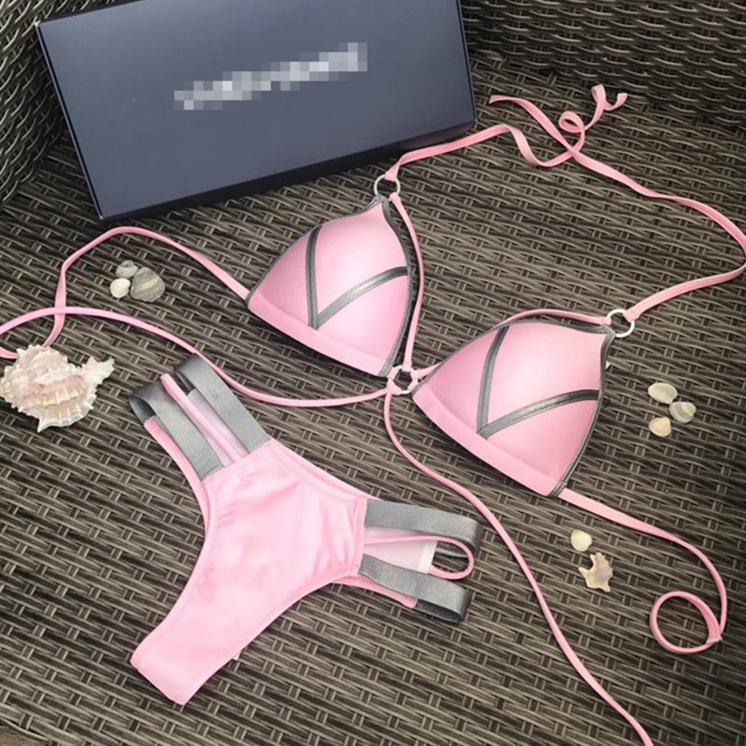 Bikini rosa a triangolo con dettagli grigi su sfondo di vimini, conchiglie decorative e scatola regalo. Costume da bagno estivo elegante.