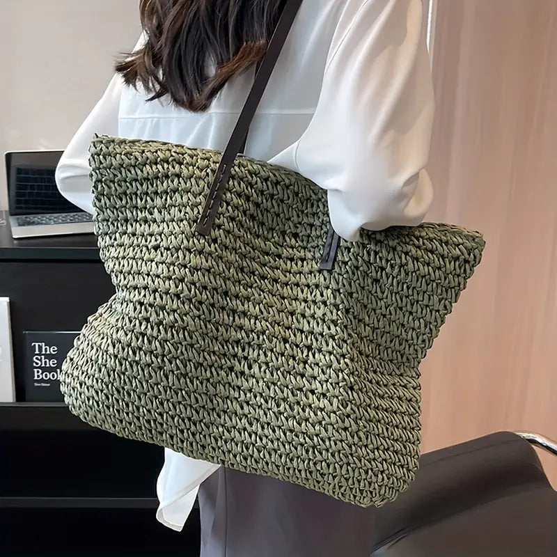 Borsa a tracolla in paglia verde, grande e intrecciata, indossata da una donna. Perfetta per l'estate, moda casual, accessorio elegante.